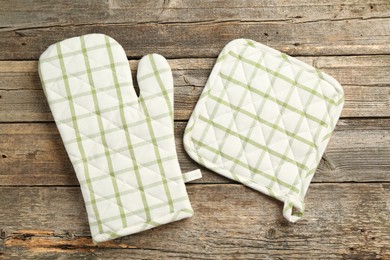 Photo of Oven glove and potholder on wooden table, flat lay