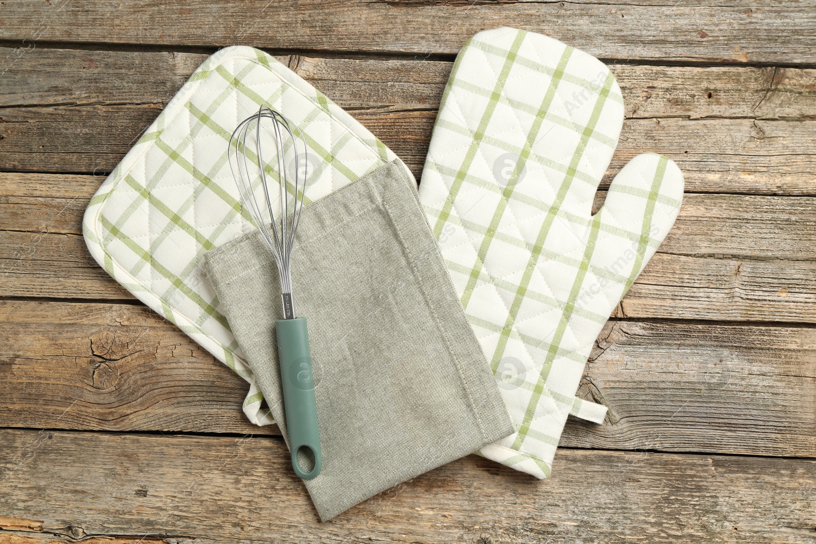 Photo of Oven glove and other kitchen utensils on wooden table, flat lay