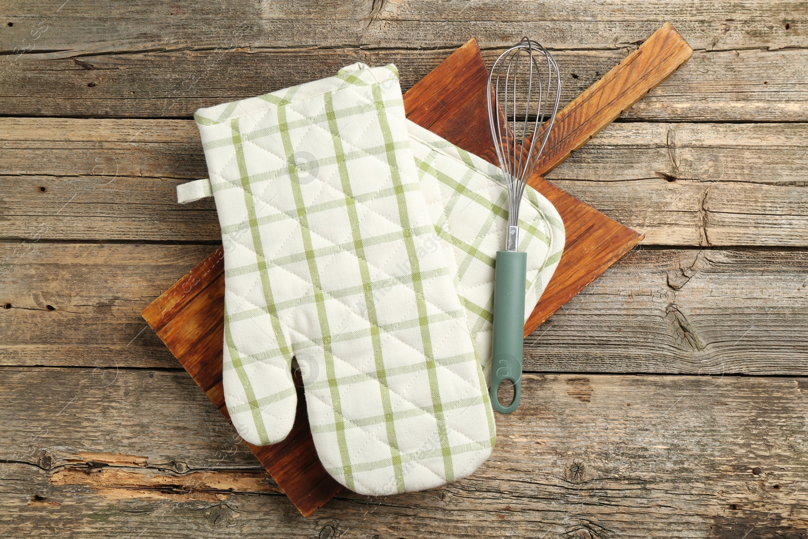 Photo of Oven glove and other kitchen utensils on wooden table, top view