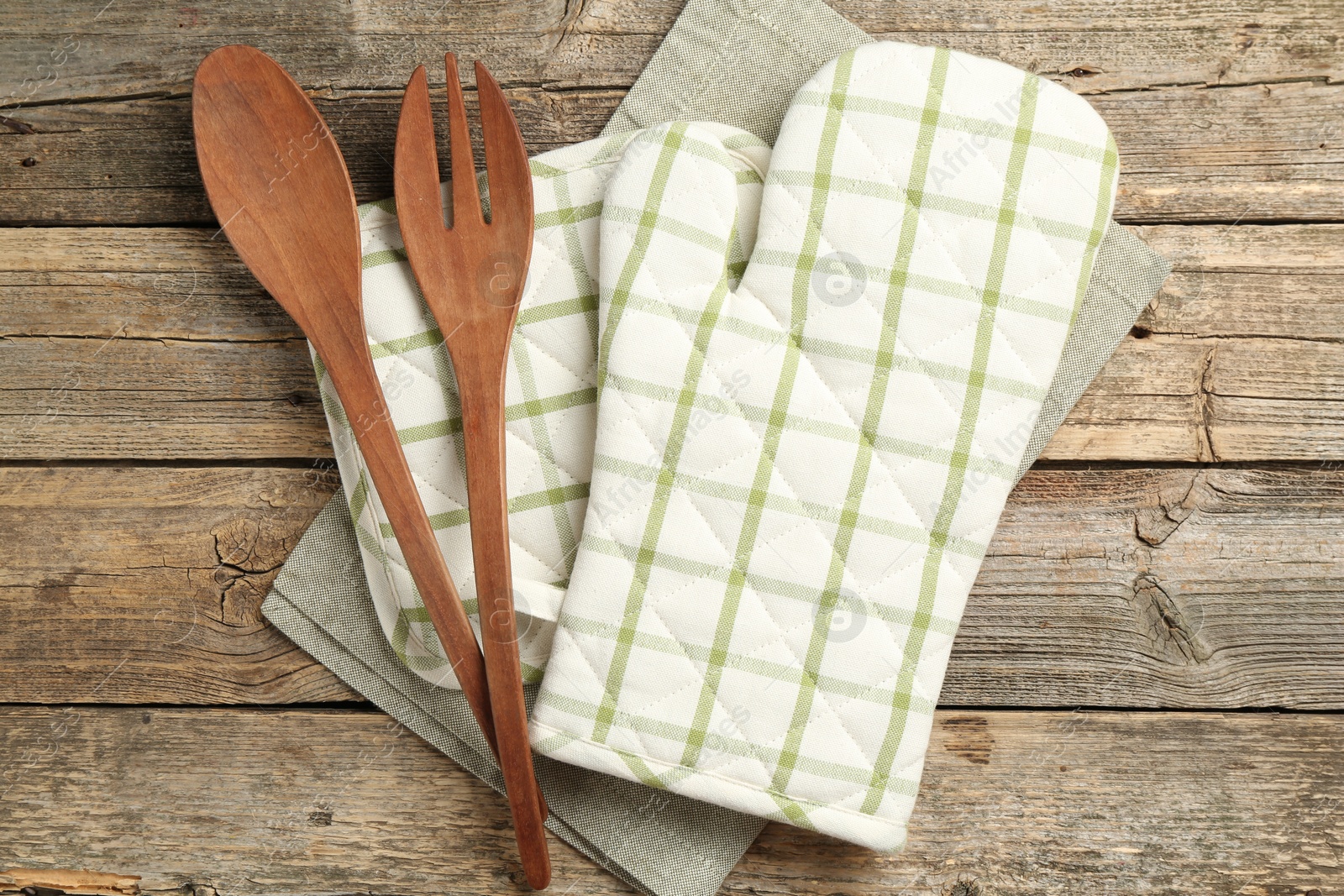 Photo of Oven glove and other kitchen utensils on wooden table, flat lay