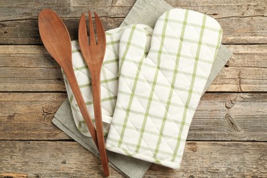 Photo of Oven glove and other kitchen utensils on wooden table, flat lay