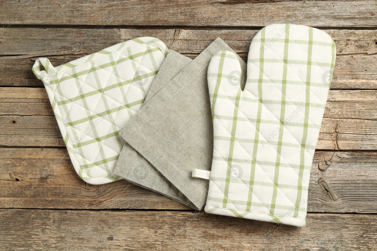 Photo of Oven glove, potholder and towel on wooden table, flat lay