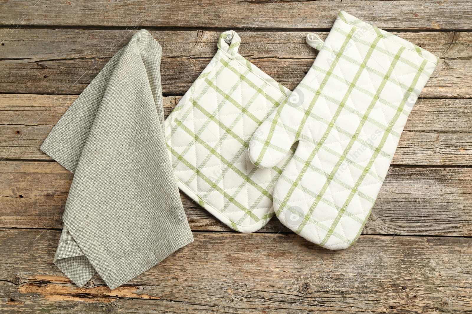 Photo of Oven glove, potholder and towel on wooden table, flat lay