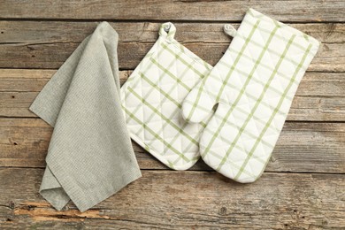 Photo of Oven glove, potholder and towel on wooden table, flat lay