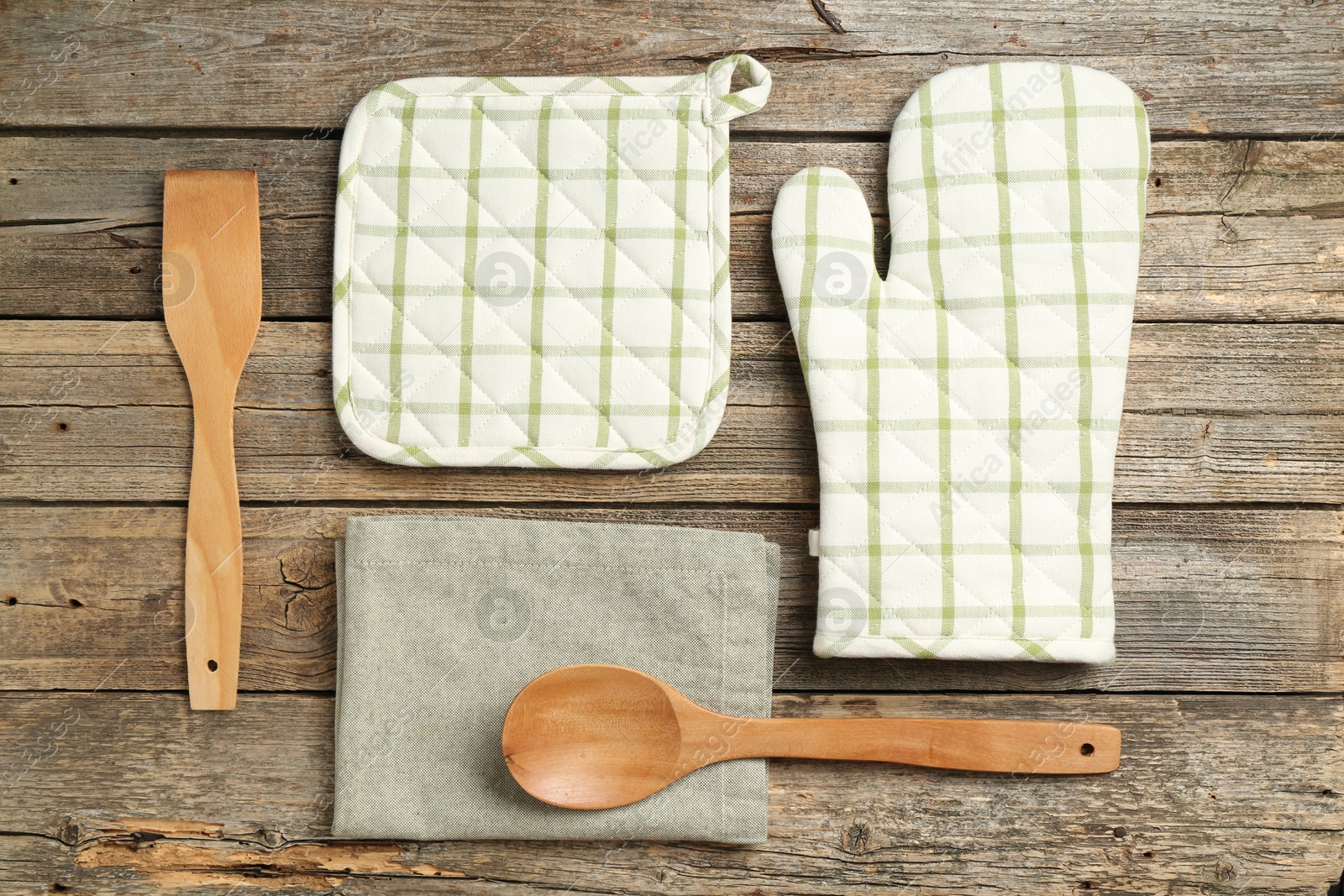 Photo of Oven glove and other kitchen utensils on wooden table, flat lay