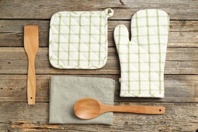 Photo of Oven glove and other kitchen utensils on wooden table, flat lay