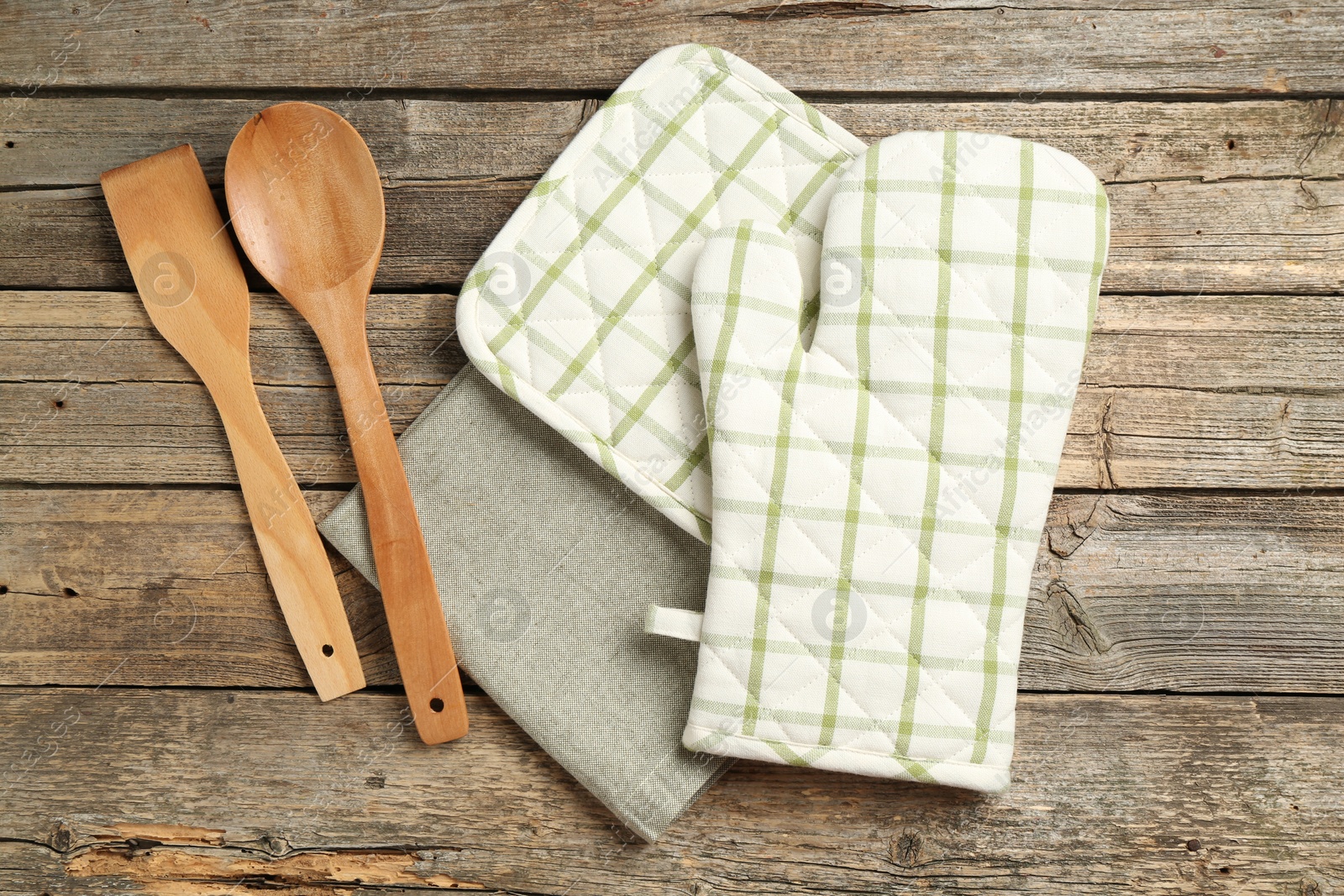 Photo of Oven glove and other kitchen utensils on wooden table, flat lay