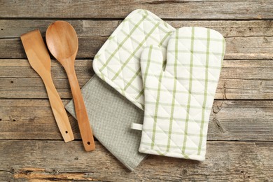 Photo of Oven glove and other kitchen utensils on wooden table, flat lay