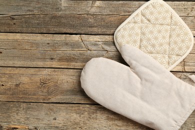 Photo of Oven glove and potholder on wooden table, flat lay. Space for text