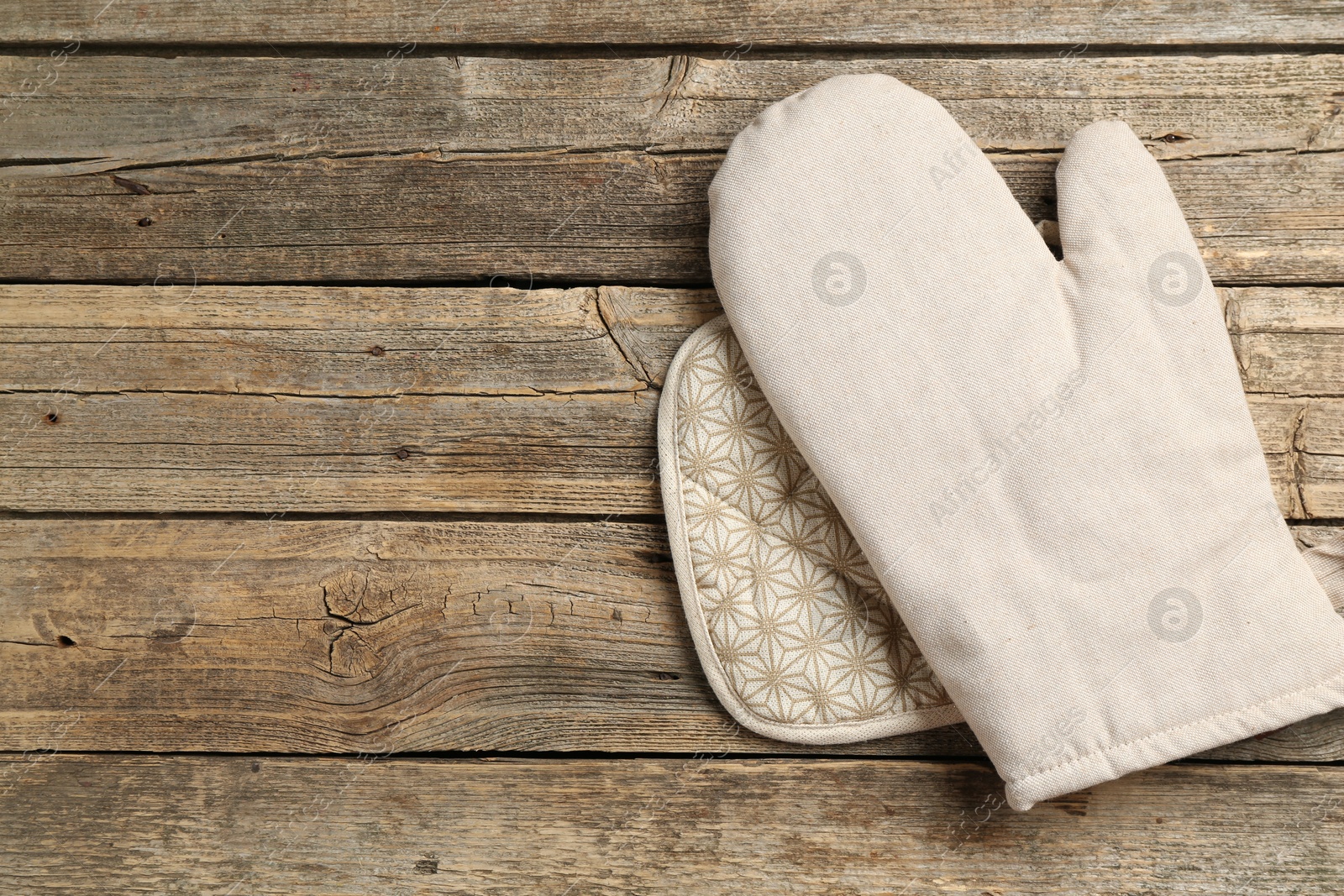 Photo of Oven glove and potholder on wooden table, top view. Space for text