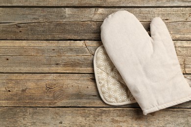 Photo of Oven glove and potholder on wooden table, top view. Space for text
