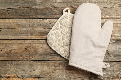 Photo of Oven glove and potholder on wooden table, top view. Space for text