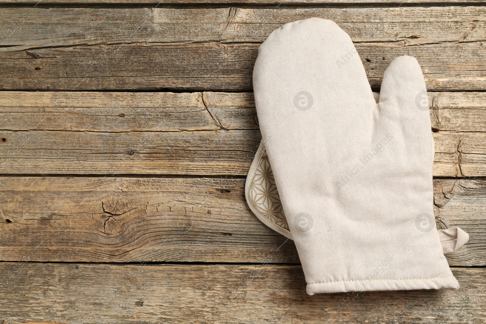 Photo of Oven glove and potholder on wooden table, top view. Space for text