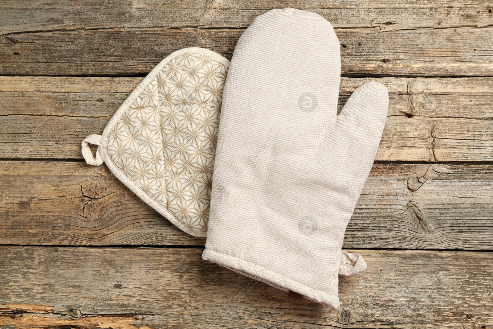 Photo of Oven glove and potholder on wooden table, top view