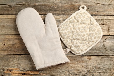 Photo of Oven glove and potholder on wooden table, flat lay
