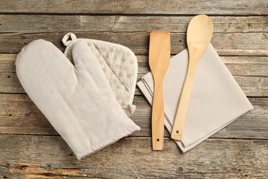 Photo of Oven glove and other kitchen utensils on wooden table, flat lay