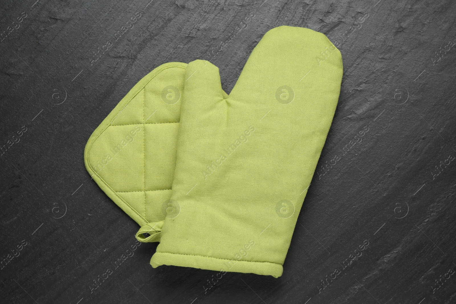 Green oven glove and potholder on dark textured table, top view Photo of Green oven glove and potholder on dark textured table, top view