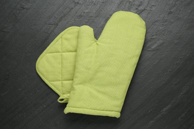 Photo of Green oven glove and potholder on dark textured table, top view