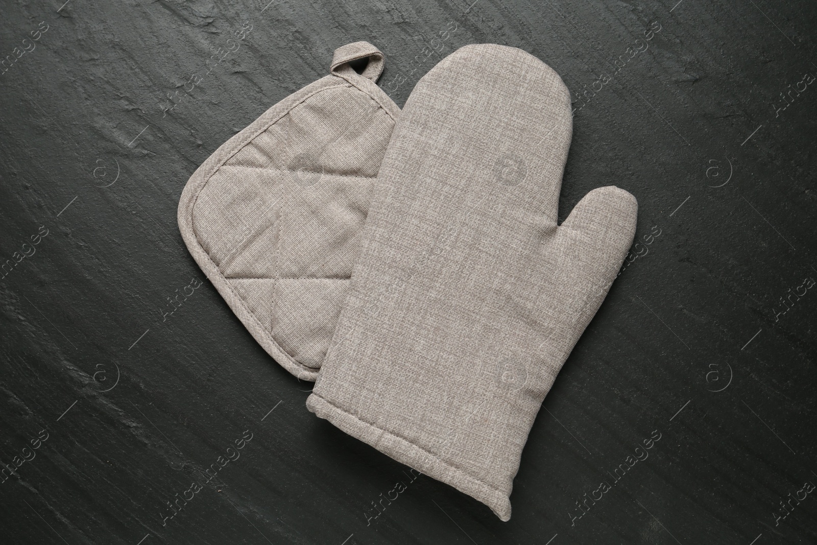 Photo of Grey oven glove and potholder on dark textured table, top view