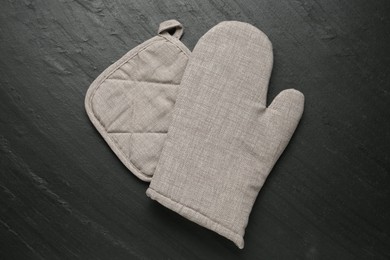 Photo of Grey oven glove and potholder on dark textured table, top view
