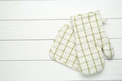 Photo of Oven glove and potholder on white wooden table, top view. Space for text