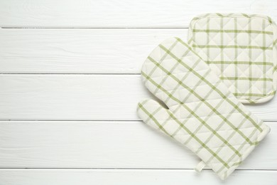 Photo of Oven glove and potholder on white wooden table, flat lay. Space for text