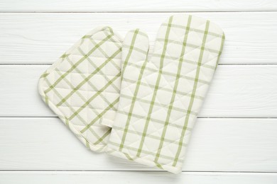 Photo of Oven glove and potholder on white wooden table, top view