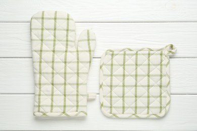 Photo of Oven glove and potholder on white wooden table, flat lay