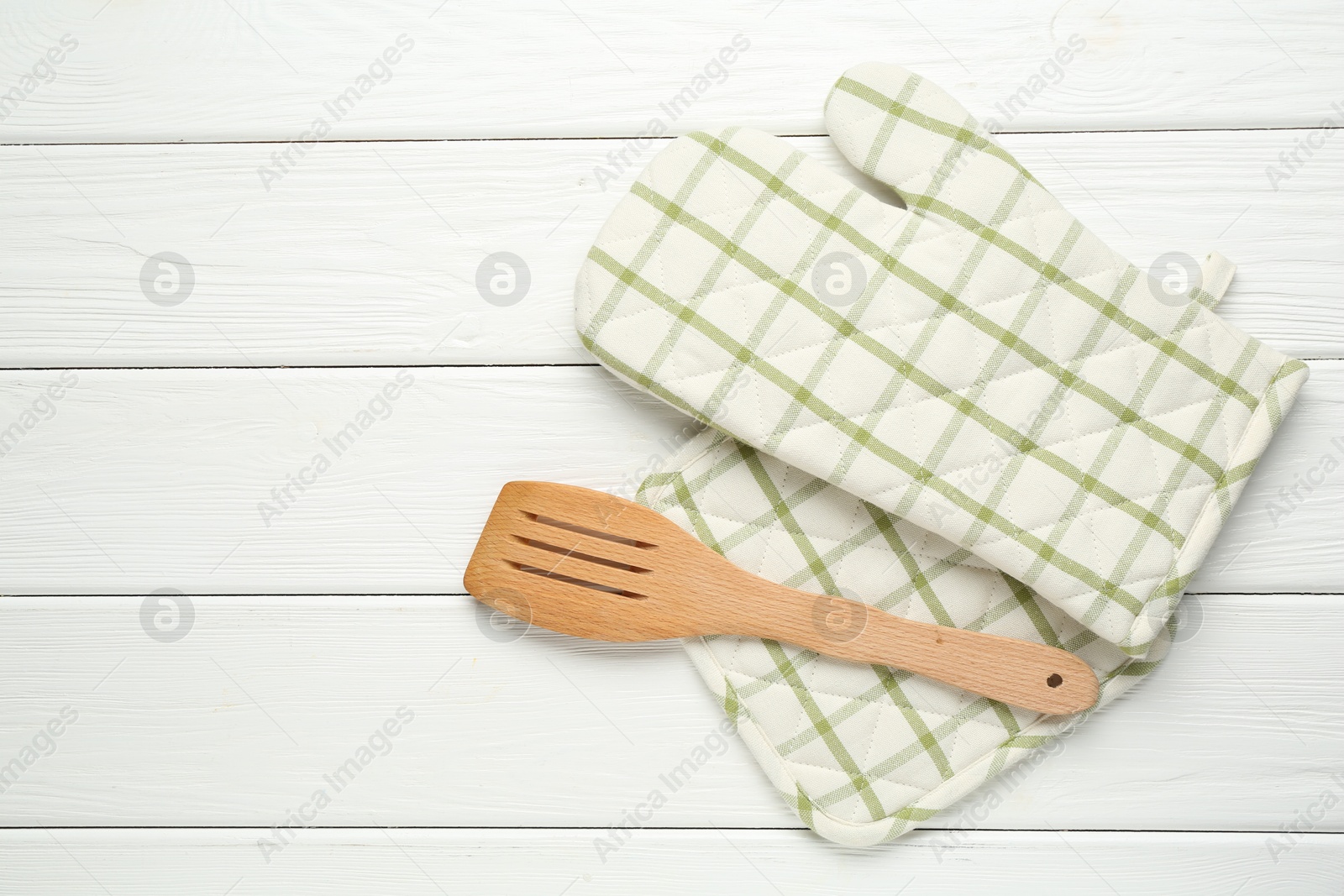 Oven glove, potholder and spatula on white wooden table, flat lay. Space for text Photo of Oven glove, potholder and spatula on white wooden table, flat lay. Space for text