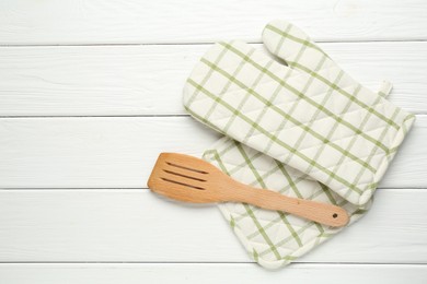 Photo of Oven glove, potholder and spatula on white wooden table, flat lay. Space for text