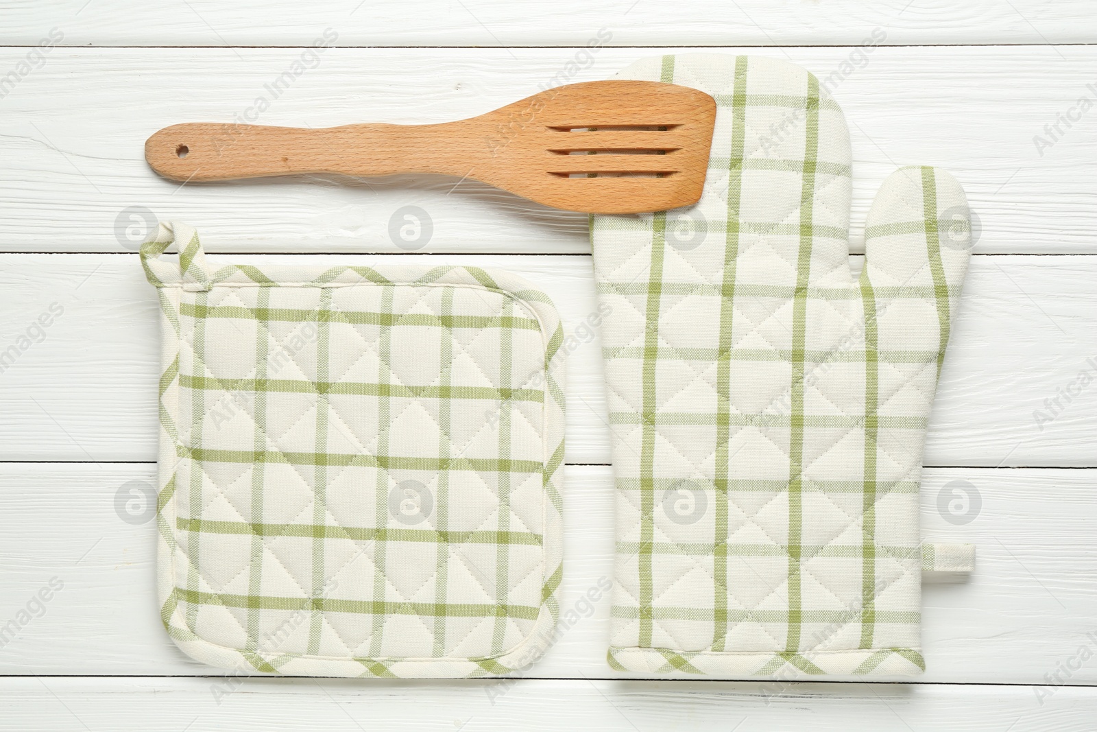 Oven glove, potholder and spatula on white wooden table, flat lay Photo of Oven glove, potholder and spatula on white wooden table, flat lay