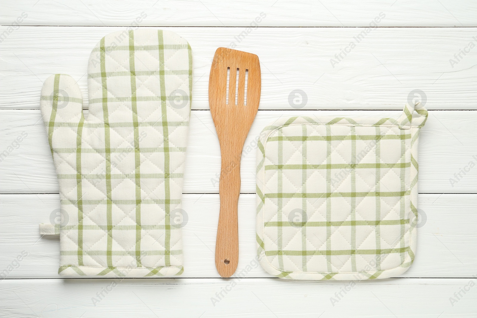 Oven glove, potholder and spatula on white wooden table, flat lay Photo of Oven glove, potholder and spatula on white wooden table, flat lay