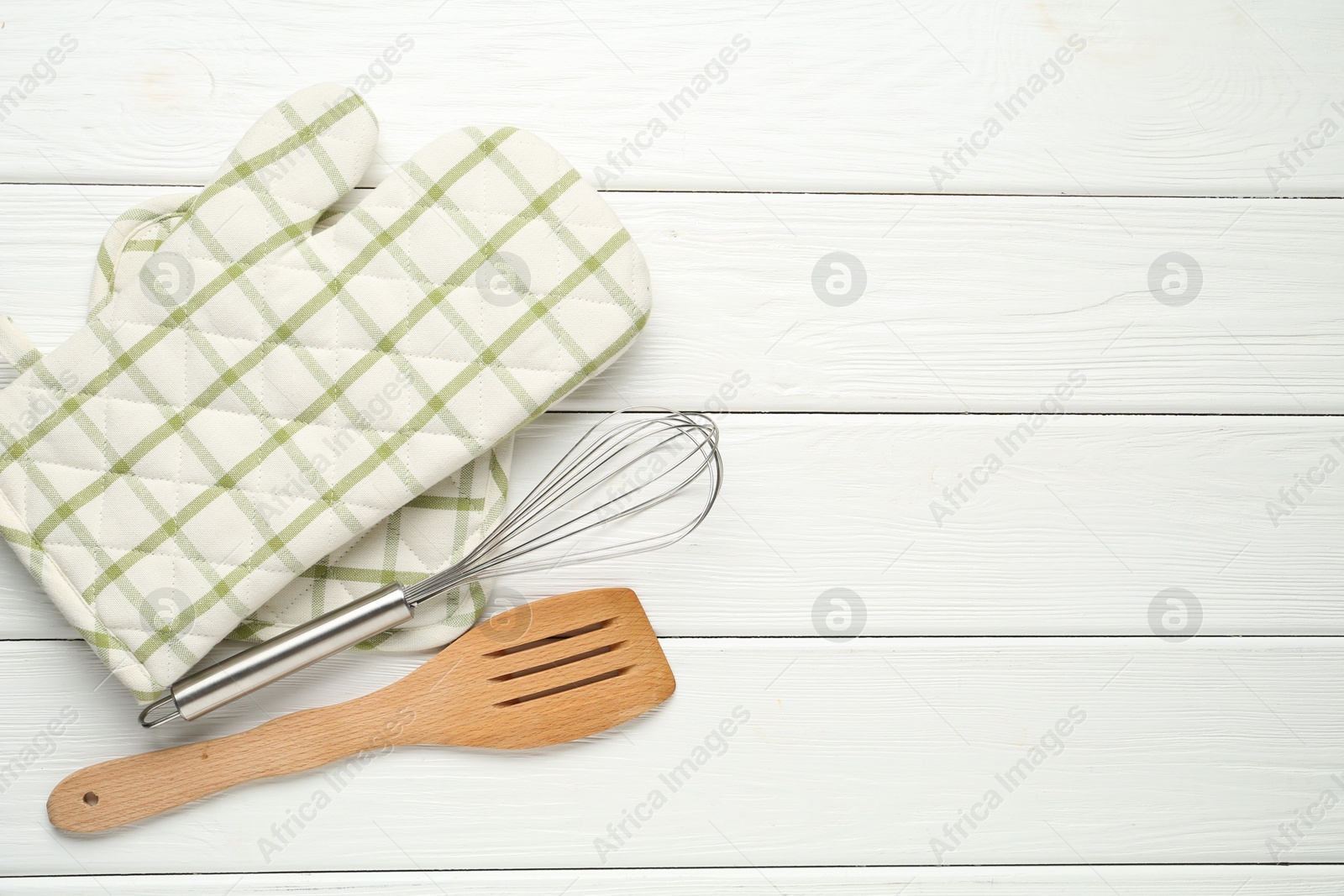 Oven glove, potholder, whisk and spatula on white wooden table, flat lay. Space for text Photo of Oven glove, potholder, whisk and spatula on white wooden table, flat lay. Space for text