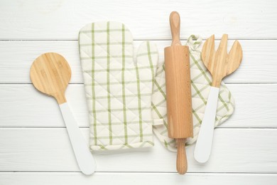Photo of Oven glove and other kitchen utensils on white wooden table, flat lay
