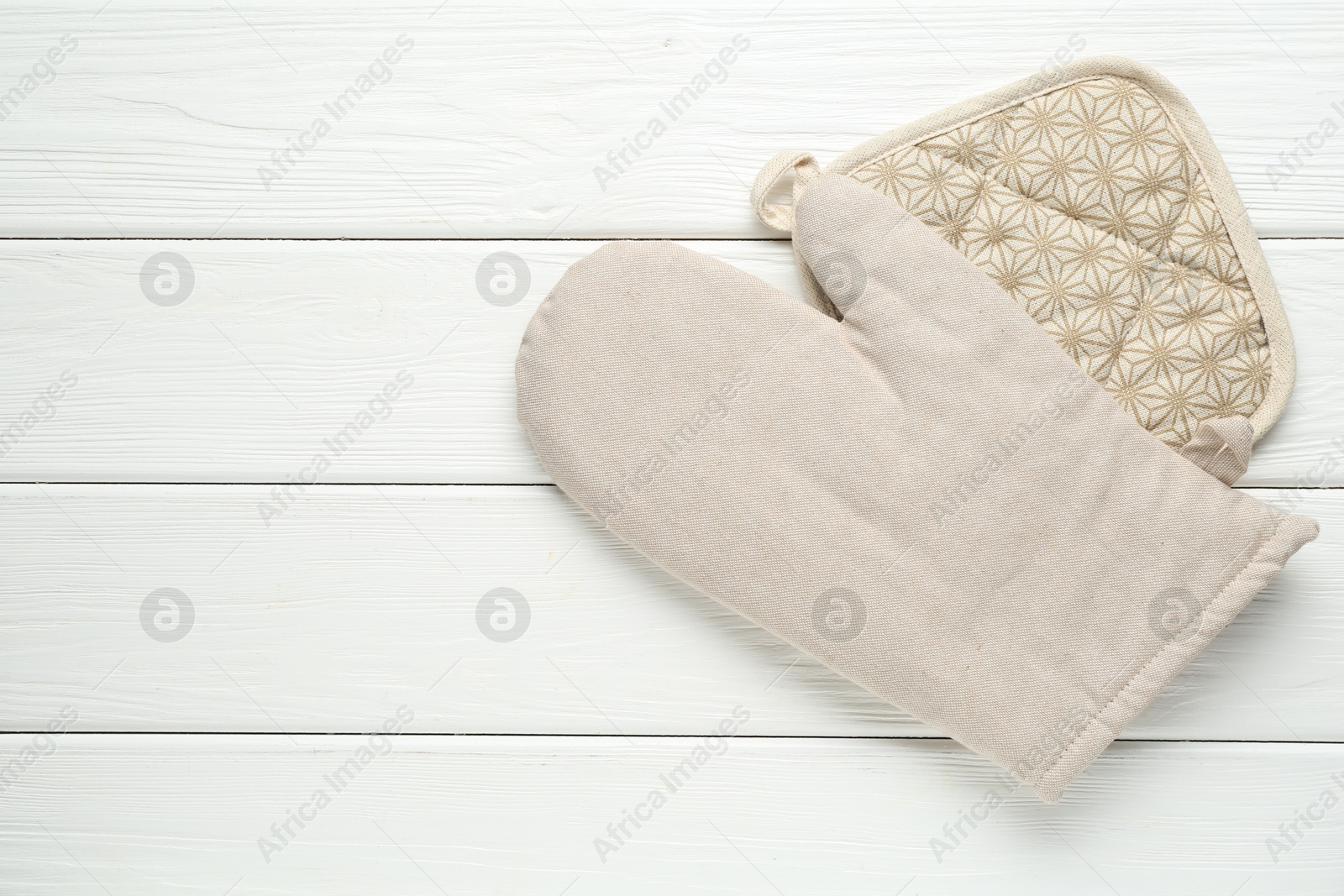 Photo of Oven glove and potholder on white wooden table, top view. Space for text