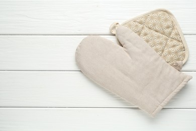 Photo of Oven glove and potholder on white wooden table, top view. Space for text