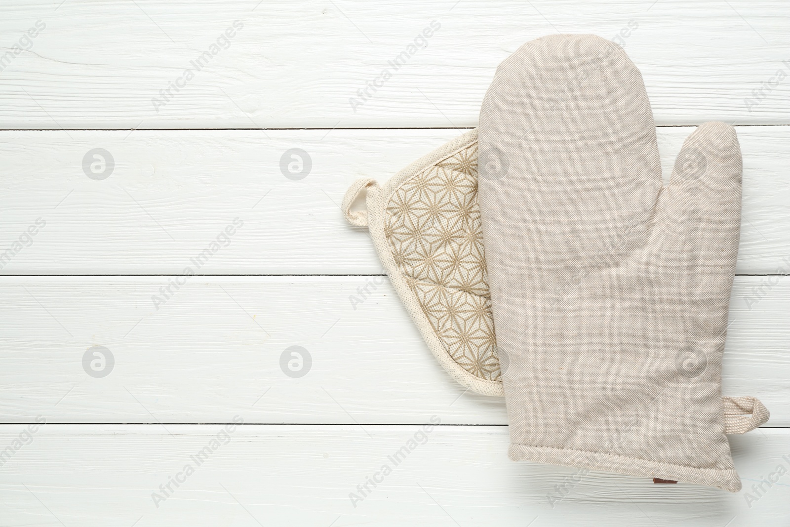 Photo of Oven glove and potholder on white wooden table, top view. Space for text