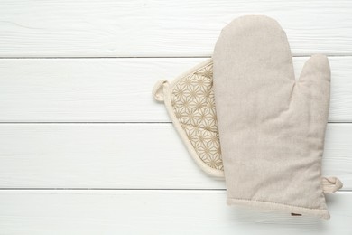 Photo of Oven glove and potholder on white wooden table, top view. Space for text