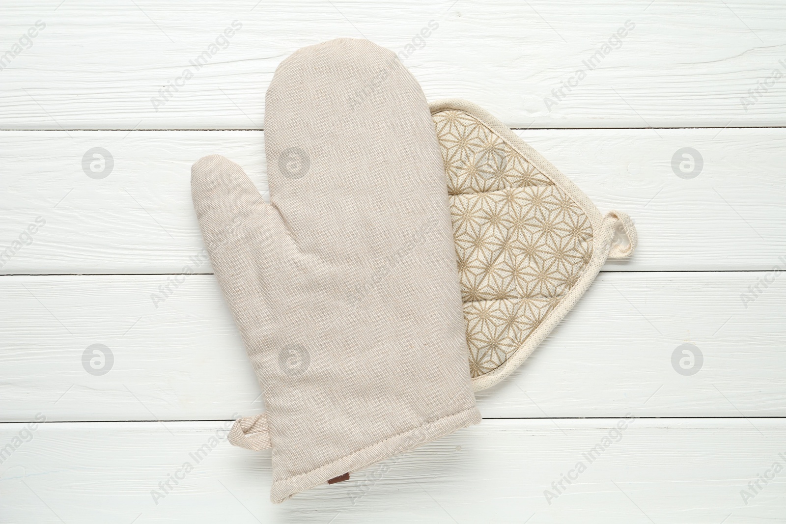 Photo of Oven glove and potholder on white wooden table, top view