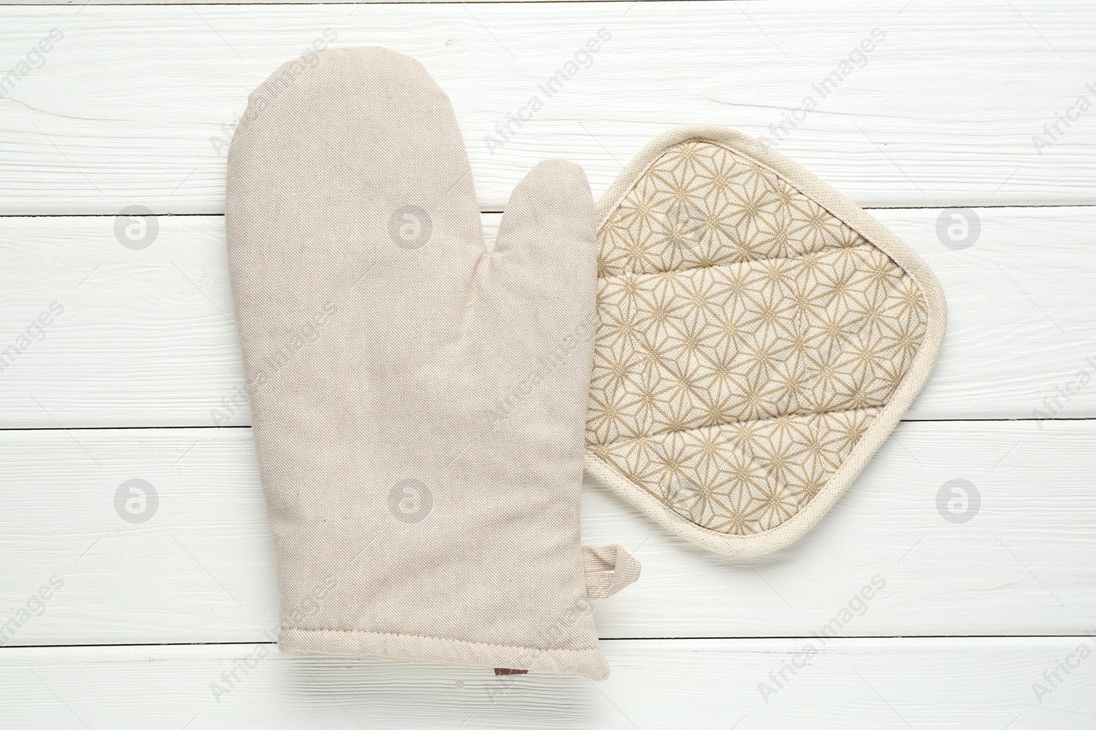 Photo of Oven glove and potholder on white wooden table, top view