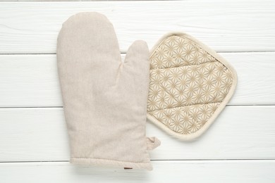 Photo of Oven glove and potholder on white wooden table, top view