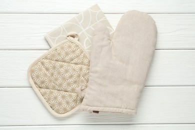 Photo of Oven glove, potholder and towel on white wooden table, top view