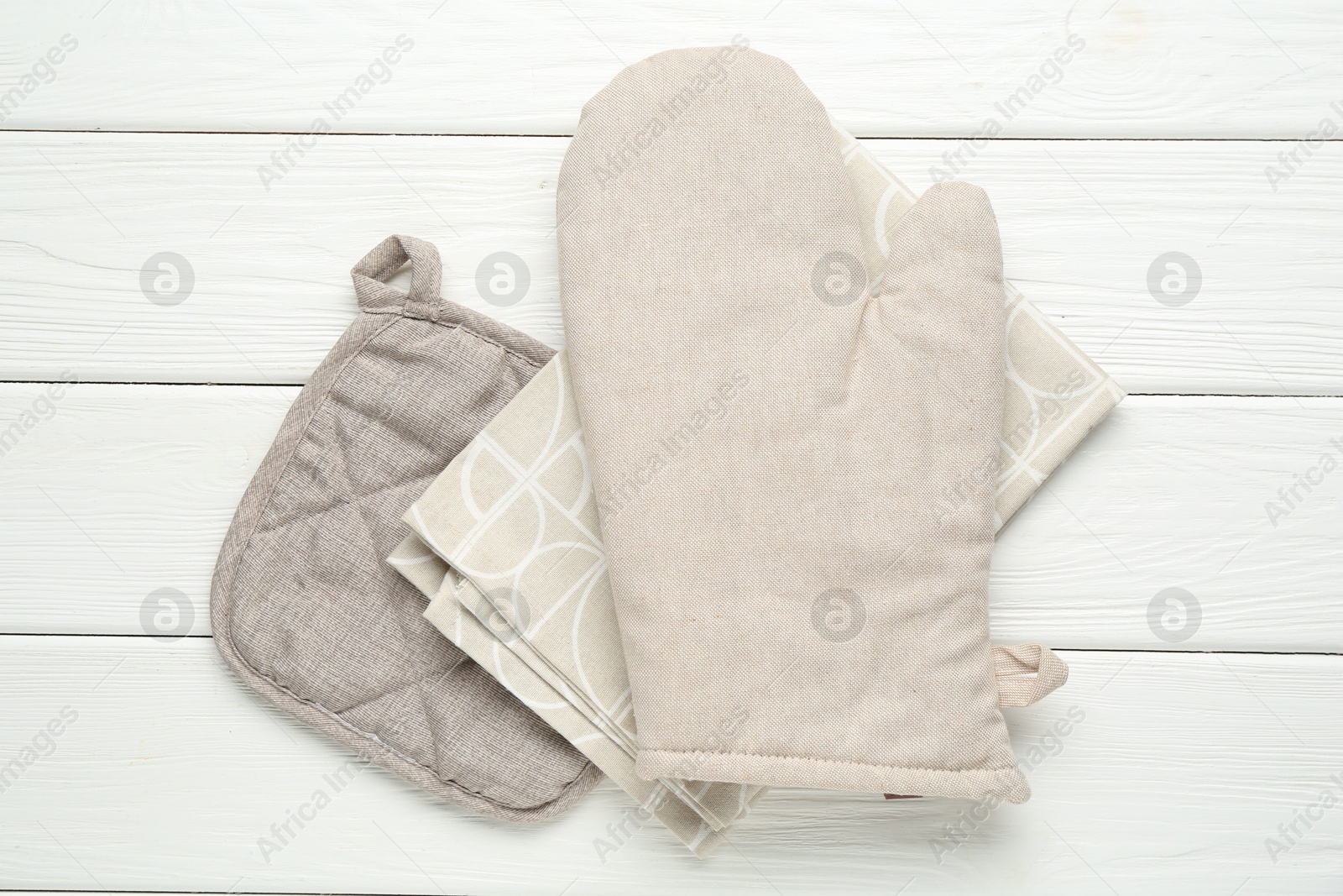 Oven glove, potholder and towel on white wooden table, top view Photo of Oven glove, potholder and towel on white wooden table, top view