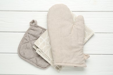 Photo of Oven glove, potholder and towel on white wooden table, top view