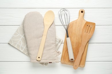 Photo of Oven glove and other kitchen utensils on white wooden table, flat lay