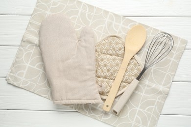 Photo of Oven glove and other kitchen utensils on white wooden table, top view