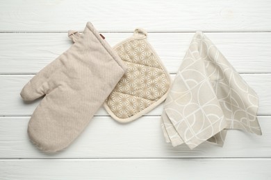 Photo of Oven glove, potholder and towel on white wooden table, flat lay