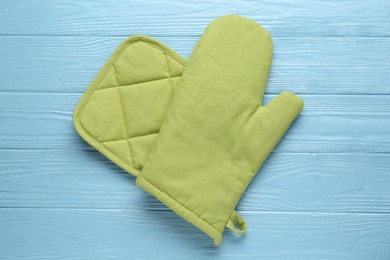 Photo of Green oven glove and potholder on light blue wooden table, top view