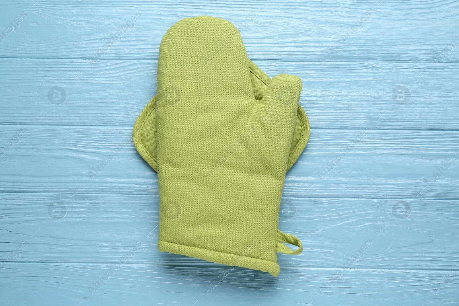 Green oven glove and potholder on light blue wooden table, top view Photo of Green oven glove and potholder on light blue wooden table, top view