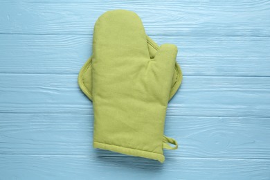 Photo of Green oven glove and potholder on light blue wooden table, top view